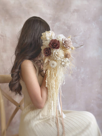 Preserved flowers cascading bridal bouquet featuring preserved roses of earthy tones, sola flower and other complementary preserved fillers.