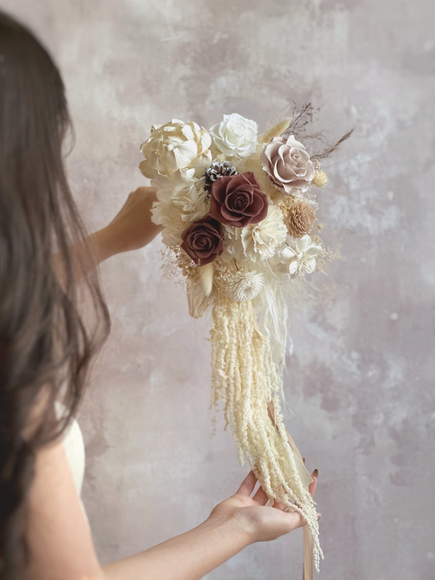 Preserved flowers cascading bridal bouquet featuring preserved roses of earthy tones, sola flower and other complementary preserved fillers in front view