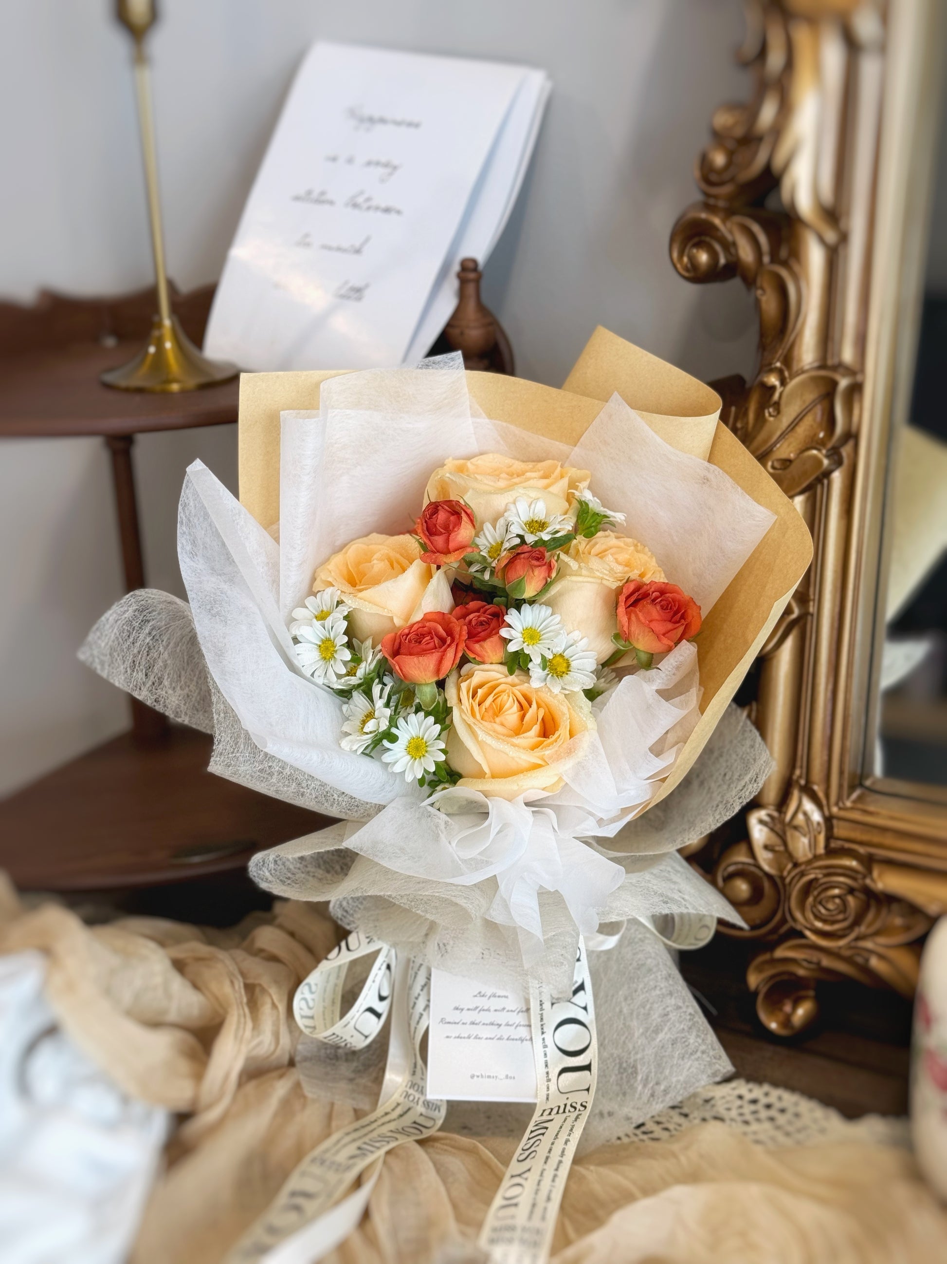 A small bouquet featuring champagne roses, orange spray roses and chamomile