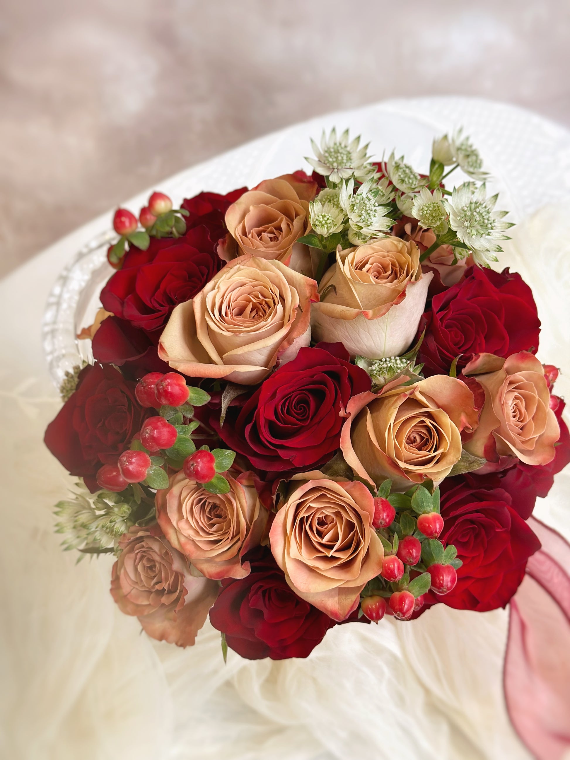 Close up view of Cherry round shaped bridal bouquet, featuring cappuccino roses and Kenyan red roses