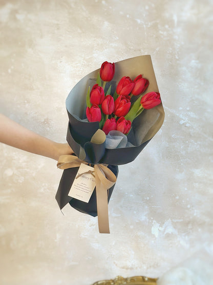 10 stalks of red tulips bouquet in sleek black wrapping style Front view 