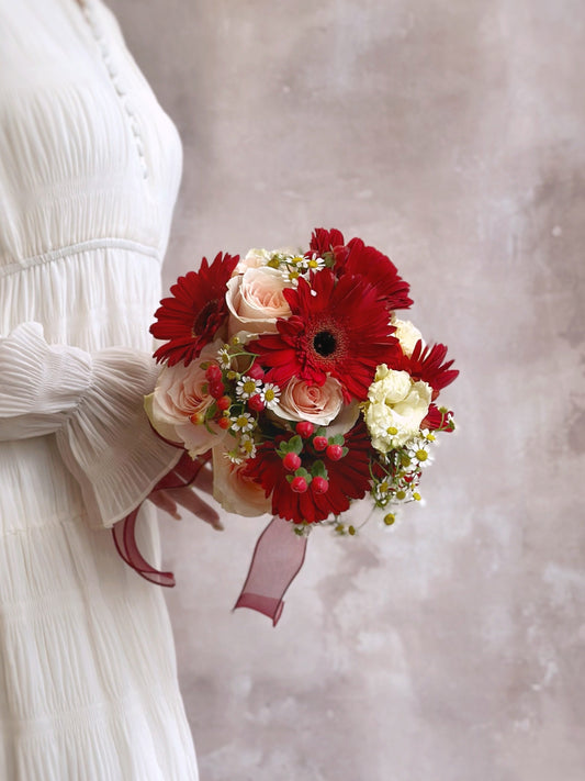 A cheerful and distinctive floral round bouquet with a rustic aesthetic, featuring red gerbera, peachy pink rose, chamomile and eustoma
充满田园气息的欢快圆形新娘捧花，展现独特魅力，红色非洲菊， 洋甘菊桃粉色玫瑰 和洋桔梗