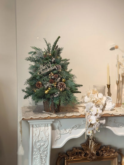 Decorative Christmas tree on a mantelpiece with ornaments and candles.