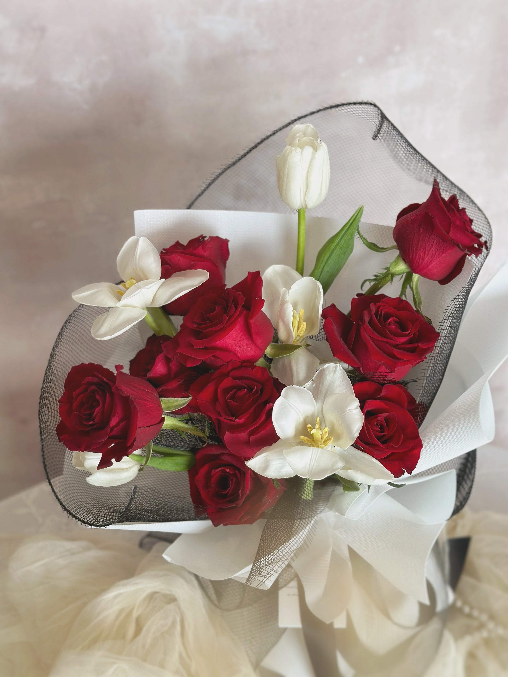 9 red roses mix with 5 stalks of white tulips, wrapped in white and black wrapper.