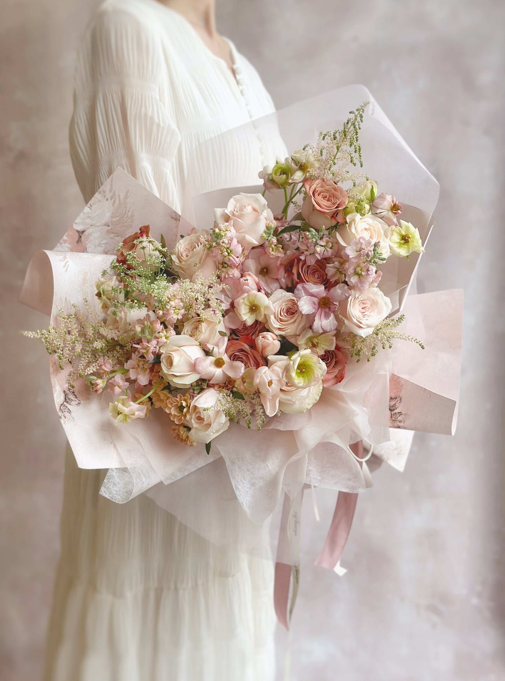  Front view of a majestic size blush pink bouquet wrapped in matching art paper and sheer ribbon, showcasing a soft and romantic design.
正面展示柔粉色系花束，搭配同色调艺术纸与薄纱丝带，整体设计柔美浪漫。