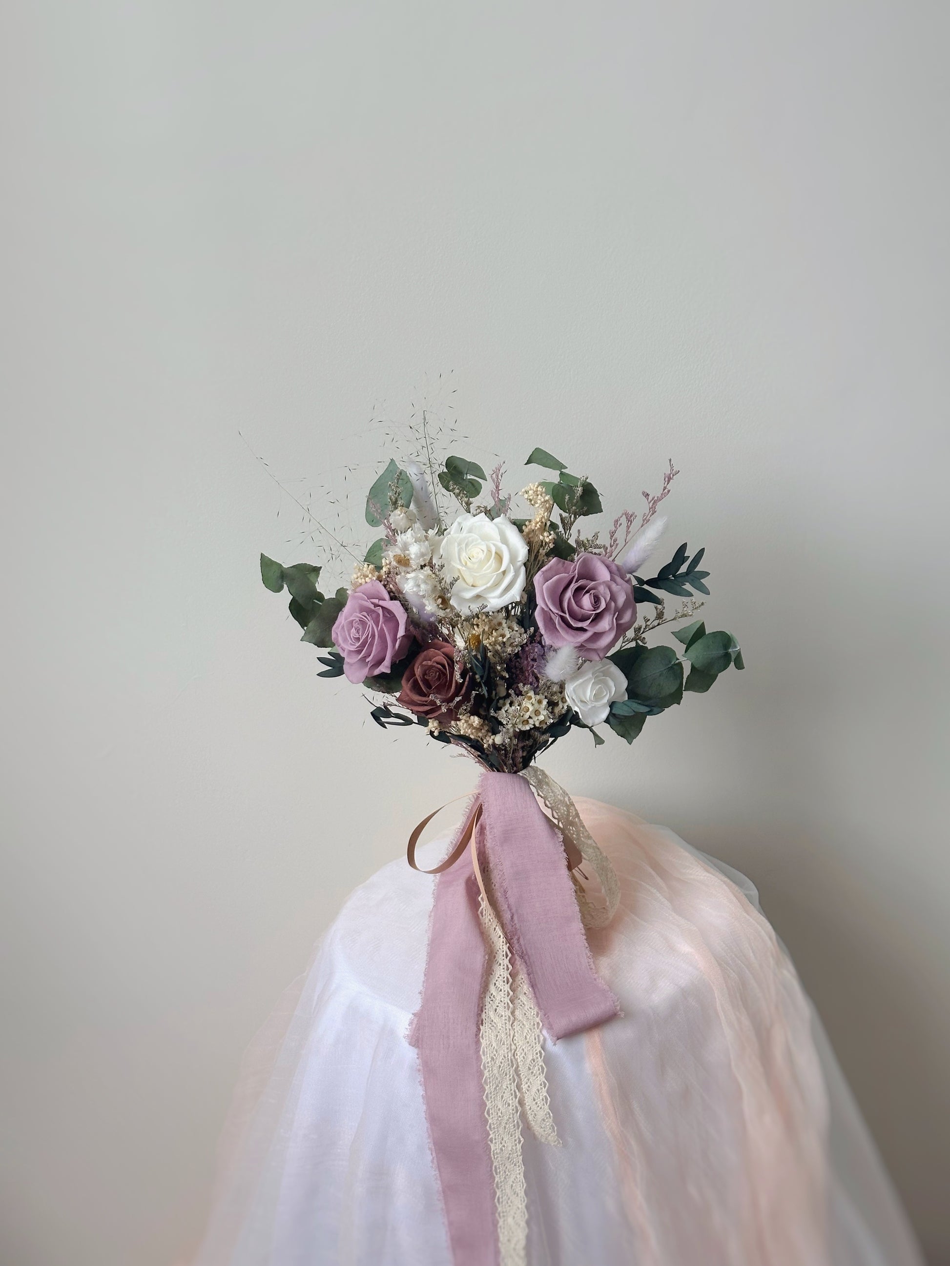 A fan-shaped preserved bouquet in soft lilac, white, and khaki tones, exuding a dreamy, romantic aesthetic.
扇形永生花捧花，采用柔和的紫丁香、白色与卡其色调，散发梦幻浪漫氛围。

