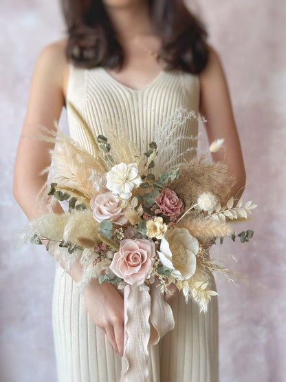 A bride holding the fan-shaped bouquet, its cascading dried elements adding a free-spirited and bohemian touch.
新娘手持扇形捧花，流畅的干花线条增添自由洒脱的波西米亚风格。