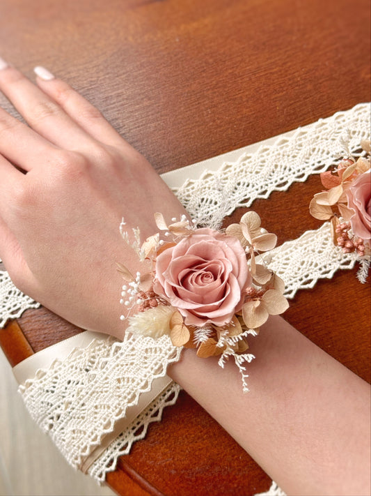 A model wearing the Lunelle preserved flowers corsage on the wrist, highlighting its pastel nude tones and romantic floral details.