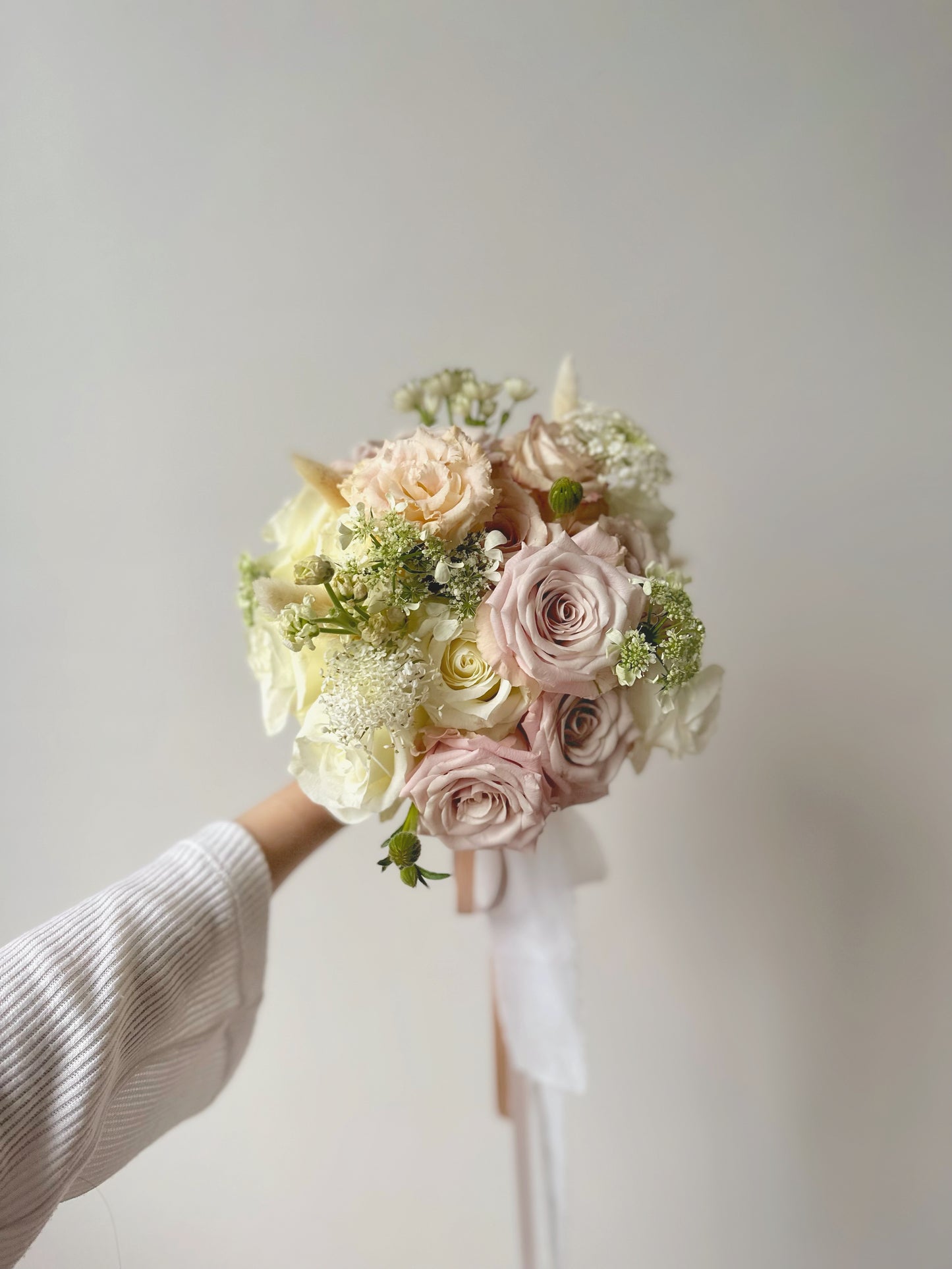 Close-up shot of the pastel rose bridal bouquet, showing delicate textures and subtle variations in the menta and quicksand rose shades.
近距离拍摄的新娘捧花，展现柔和的曼塔玫瑰和流沙玫瑰花瓣质感和细腻的色彩变化。