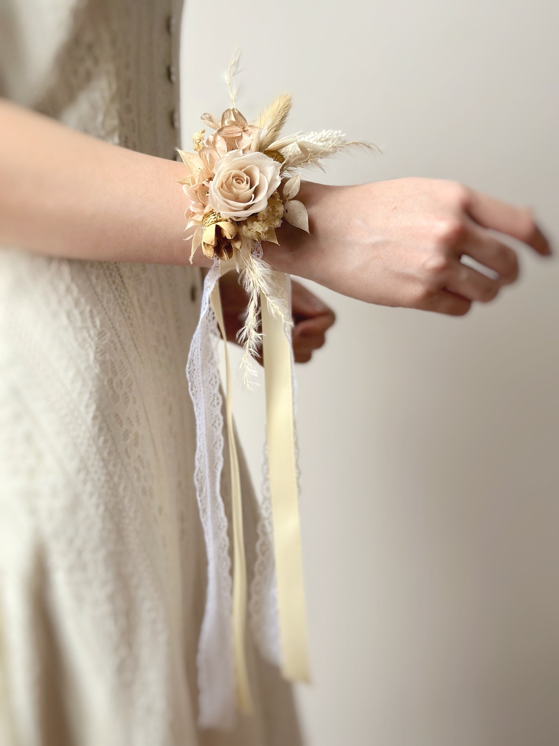 Close-up of a model wearing a lace-adorned Champagne-toned everlasting rose wrist corsage, showcasing its elegant and timeless design.