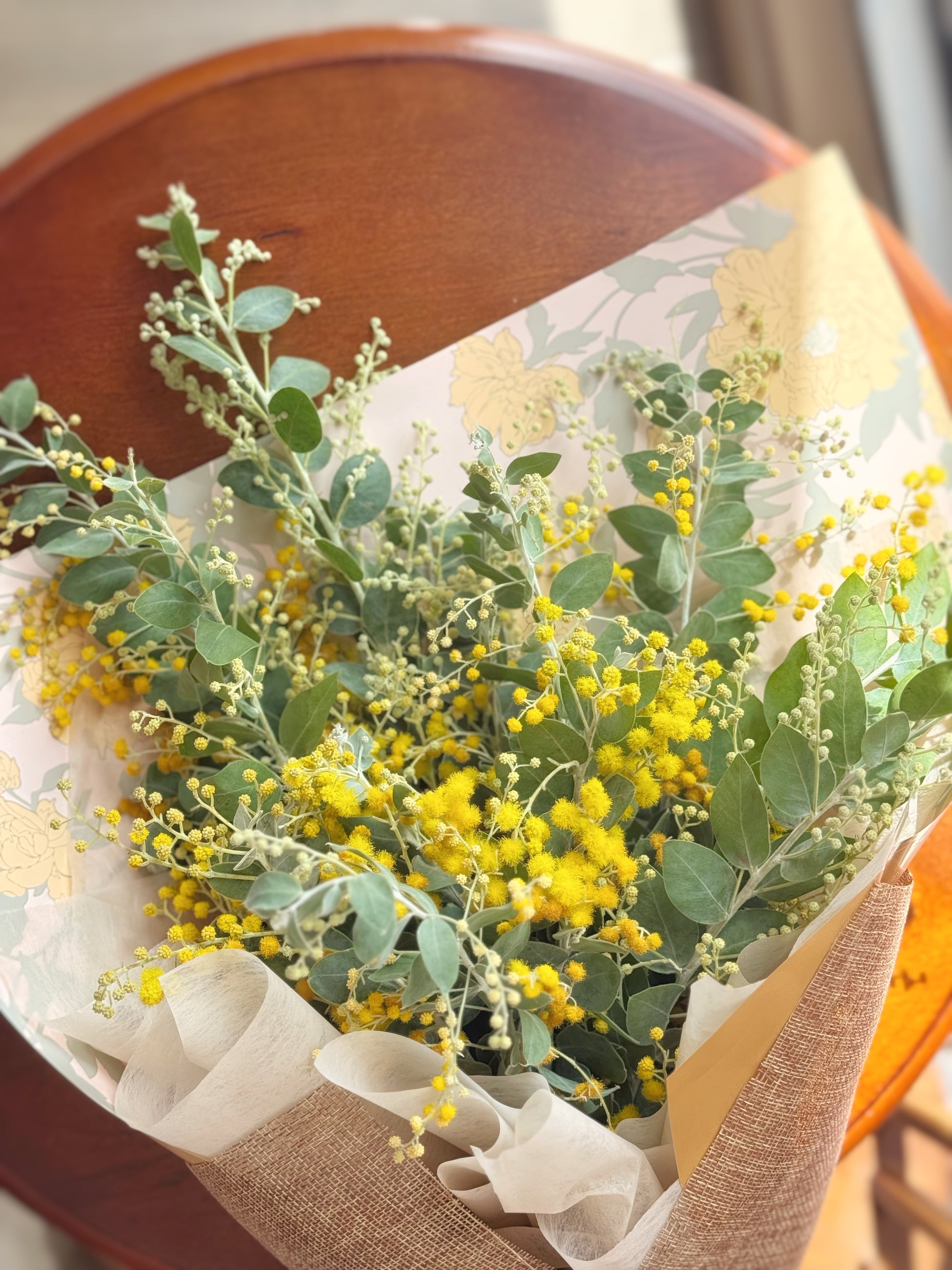 Close-up of yellow acacia blooms in a hand-tied bouquet with soft, fluffy texture.
黄金花束特写，绒球状花朵质感柔软。