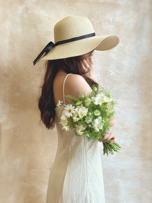 A fairy-like ivory wildflower bouquet held by a model, showcasing its soft, cascading greenery and delicate ivory blooms. Perfect for an elegant and whimsical bridal look.

 模特手持象牙色野花捧花，展现轻盈飘逸的绿叶和精致的花朵，为新娘带来优雅梦幻的婚礼造型。
