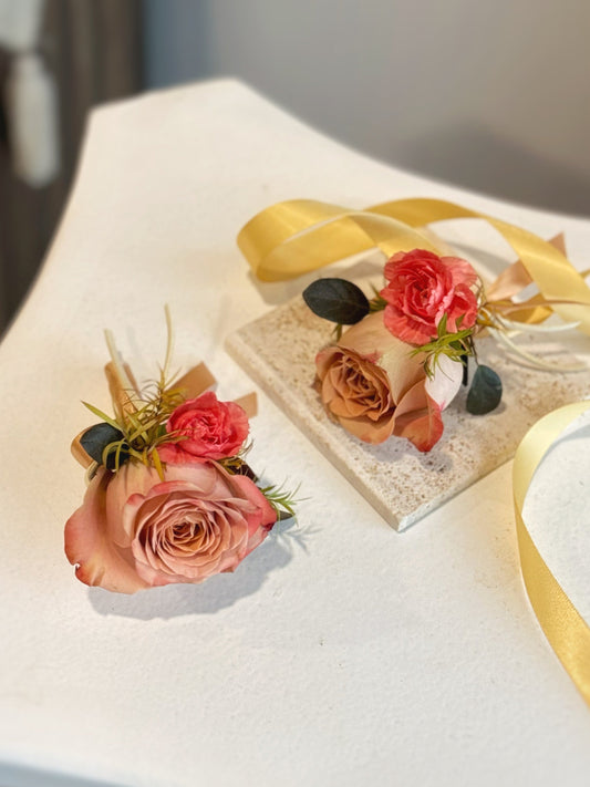 Mocha sunset fresh rose wrist corsage and boutonniere lying elegantly on the table