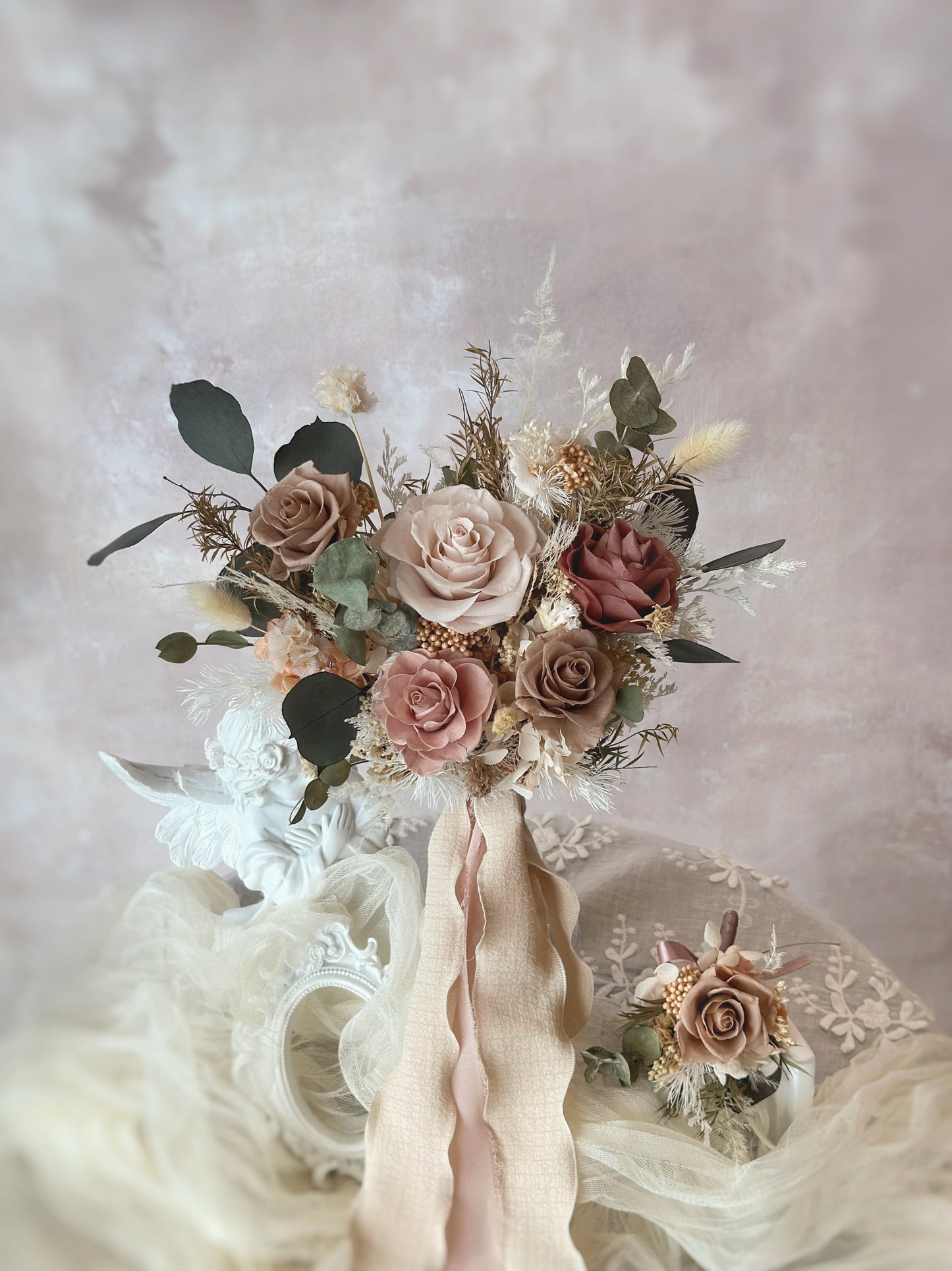 A delicate preserved flower corsage in neutral earthy tones, designed to pair effortlessly with the bridal bouquet. A preserved bridal bouquet in soft neutral and earthy tones, evoking a sense of calm and natural beauty.
一款柔和中性色调与大地色系的永生花新娘捧花，散发宁静自然的美感。
一款中性色调的精致永生花胸花，与新娘捧花相得益彰。