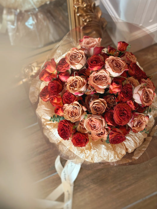 Top-down view of a compact fresh flowers round bouquet with balanced placement of cappuccino and chocolate bubble spray roses, framed with eucalyptus.

俯视图展示紧凑圆形鲜花花束，卡布奇诺玫瑰与复古巧克力泡泡多头玫瑰交错排列，尤加利叶自然点缀，色彩协调。
