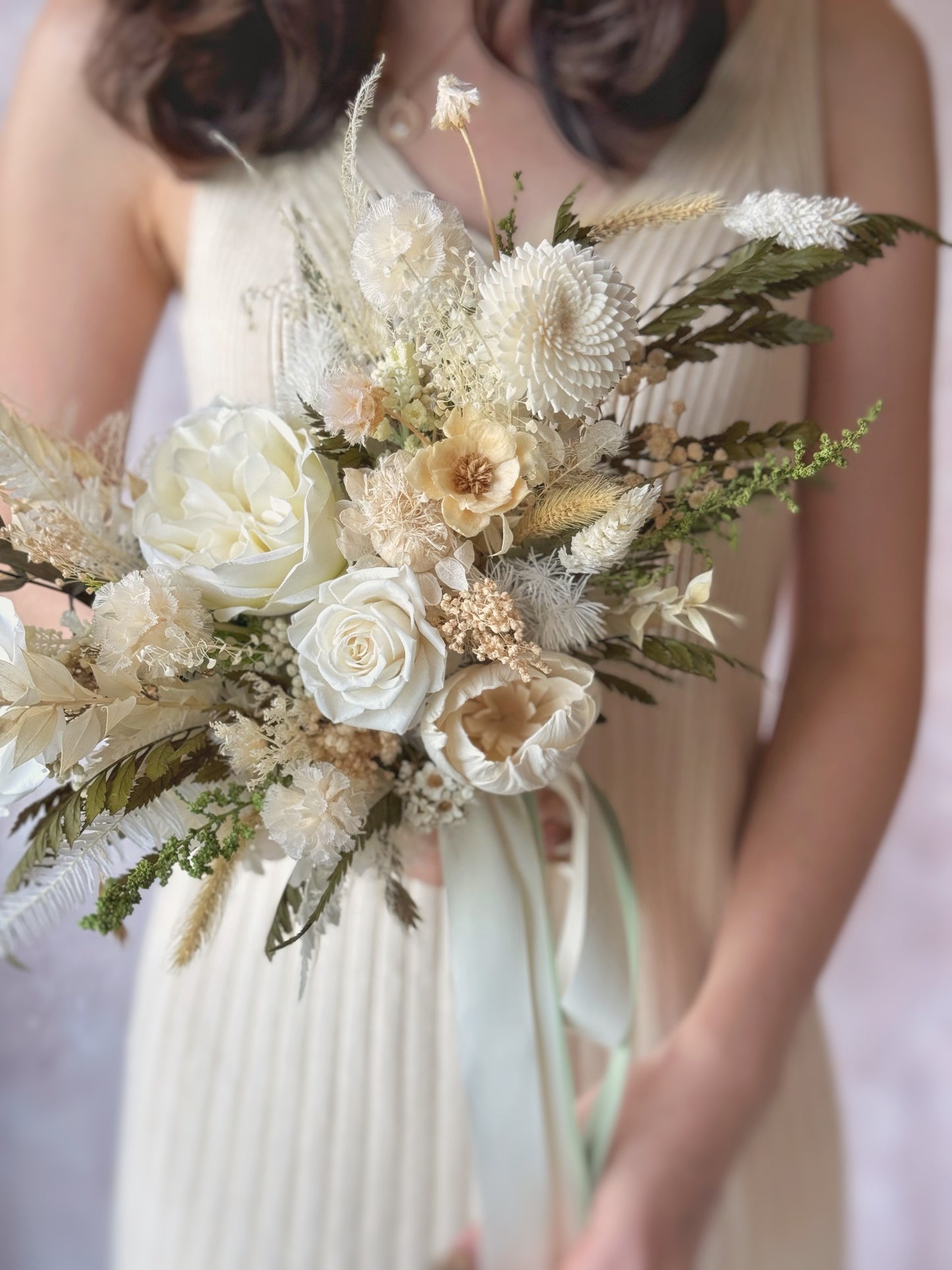 A detailed close-up of the bouquet, showcasing the intricate mix of textures and airy, wispy fern leaves.
捧花特写镜头，展现丰富层次的花材与轻盈的蕨叶细节。