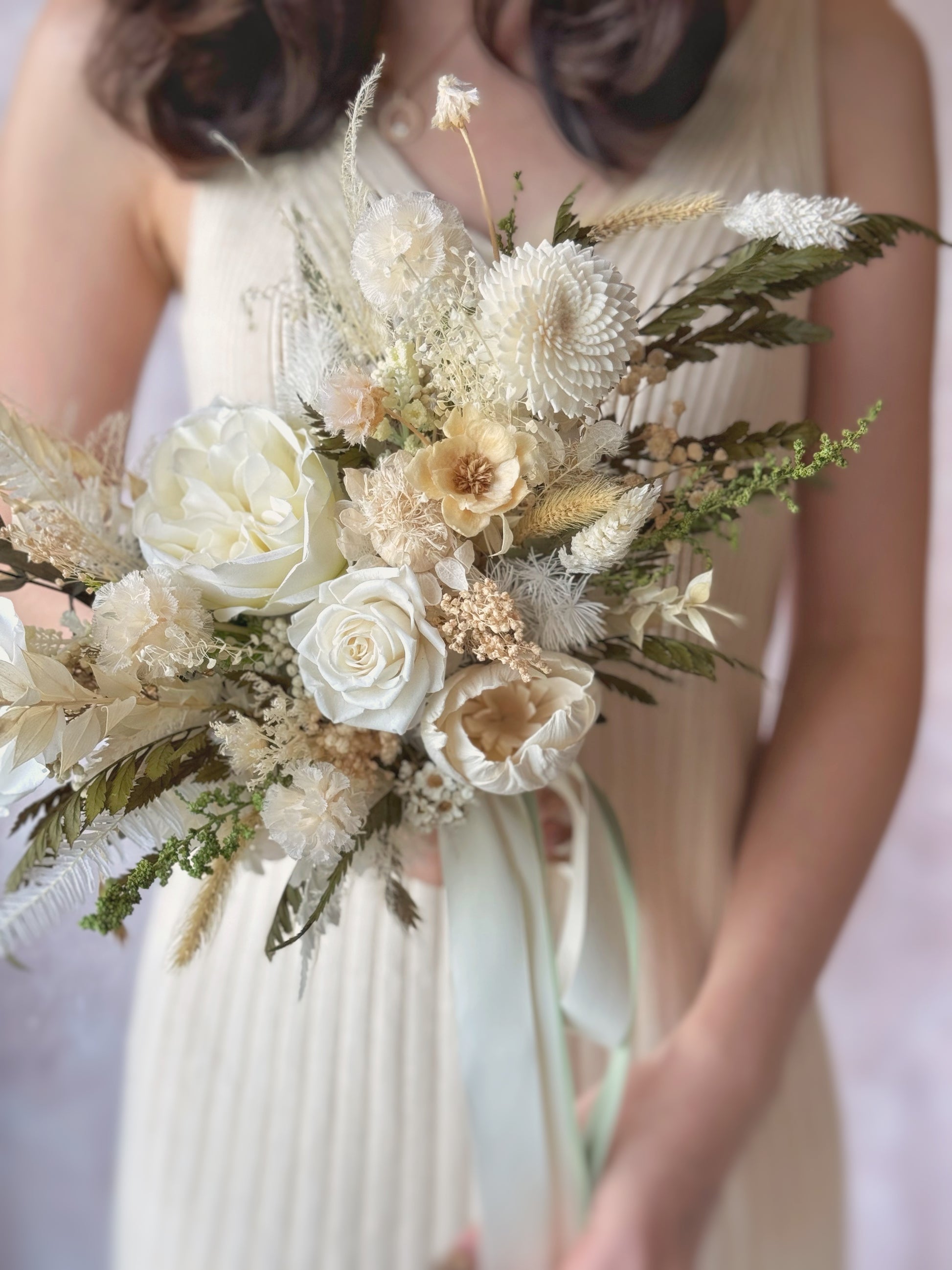 A detailed close-up of the bouquet, showcasing the intricate mix of textures and airy, wispy fern leaves.
捧花特写镜头，展现丰富层次的花材与轻盈的蕨叶细节。