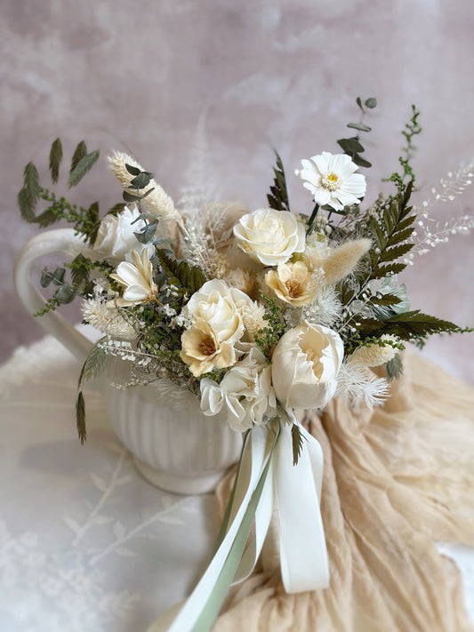 A wild garden-inspired bridal bouquet featuring delicate white flowers, creamy blooms, and airy fern accents.
一款灵感源自野生花园的新娘捧花，点缀细腻白色小花、柔和奶油色花朵及轻盈蕨叶。
