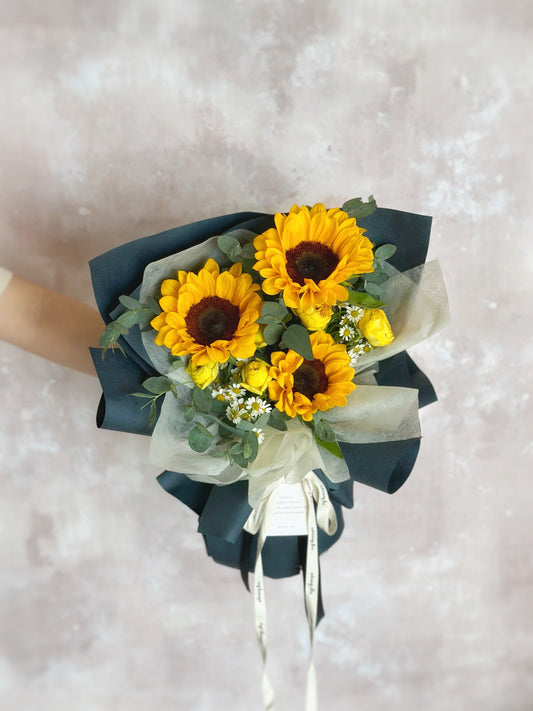 Front view of a masculine sunflower bouquet named Noah for graduation or convocation, featuring bright yellow blooms wrapped in bold navy blue paper for a strong, confident look.

正面展示男士风格毕业花束 Noah，鲜艳向日葵搭配深藏青色包纸，呈现阳光与沉稳的视觉冲击