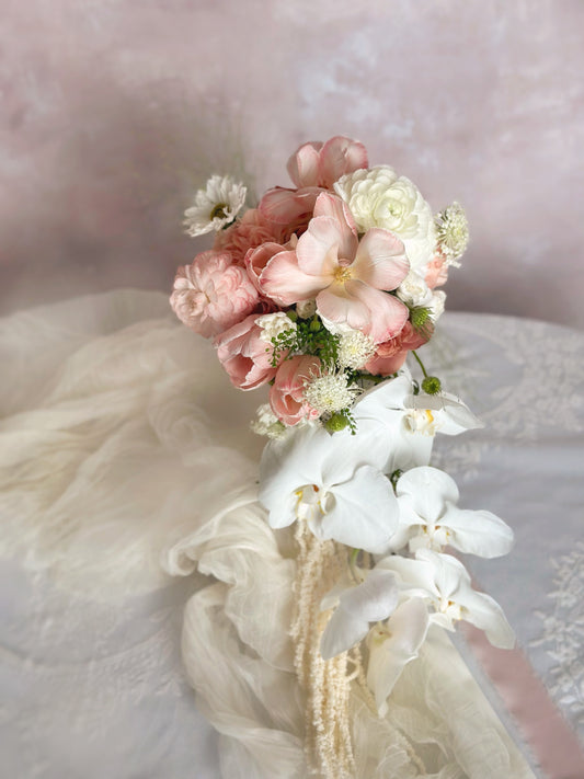 A cascading phalaenopsis and tulips mix bridal bouquet in soft peachy pink tones, perfect for a romantic wedding look
柔和蝴蝶兰郁金香蜜桃粉色系瀑布式新娘捧花，营造浪漫婚礼氛围