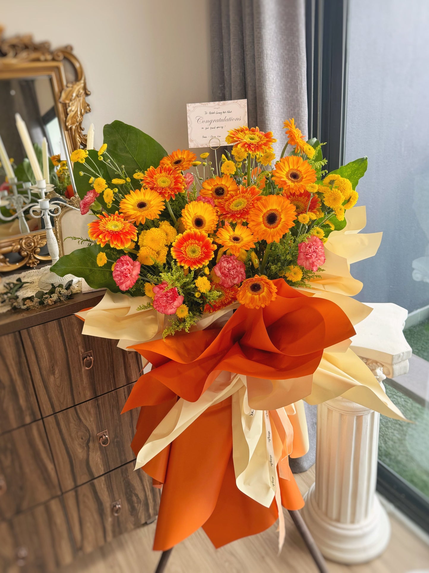 Fresh flower stand bursting with vivid orange and sunny yellow gerberas, accented with greenery for a radiant and celebratory grand opening décor