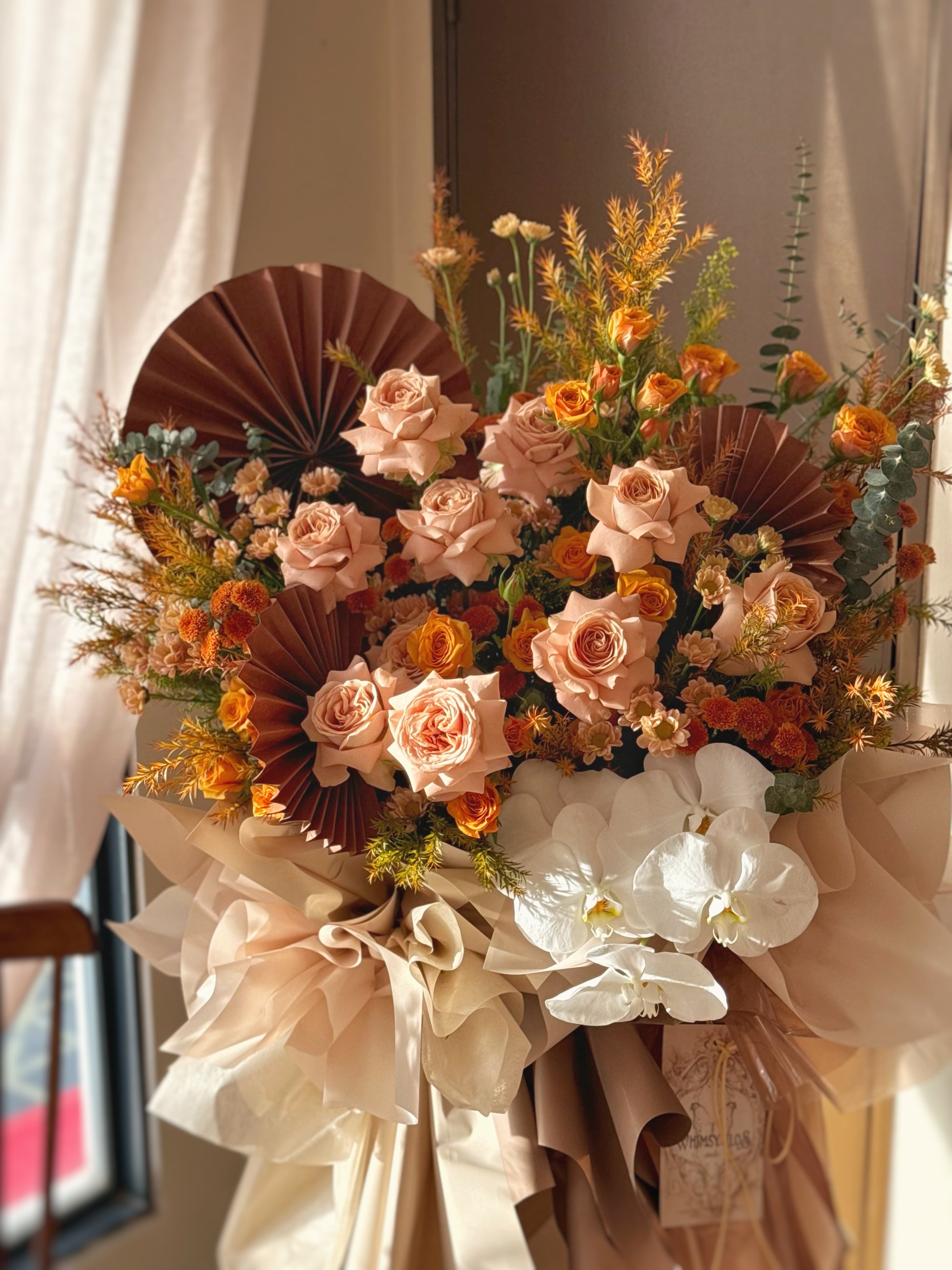 Close-up of cappuccino roses with velvety petals in rich amber and beige, enhanced by earthy fillers and leafy accents.

焦糖玫瑰特写，琥珀与米色花瓣细腻柔滑，搭配泥土色配花与绿叶更显质感