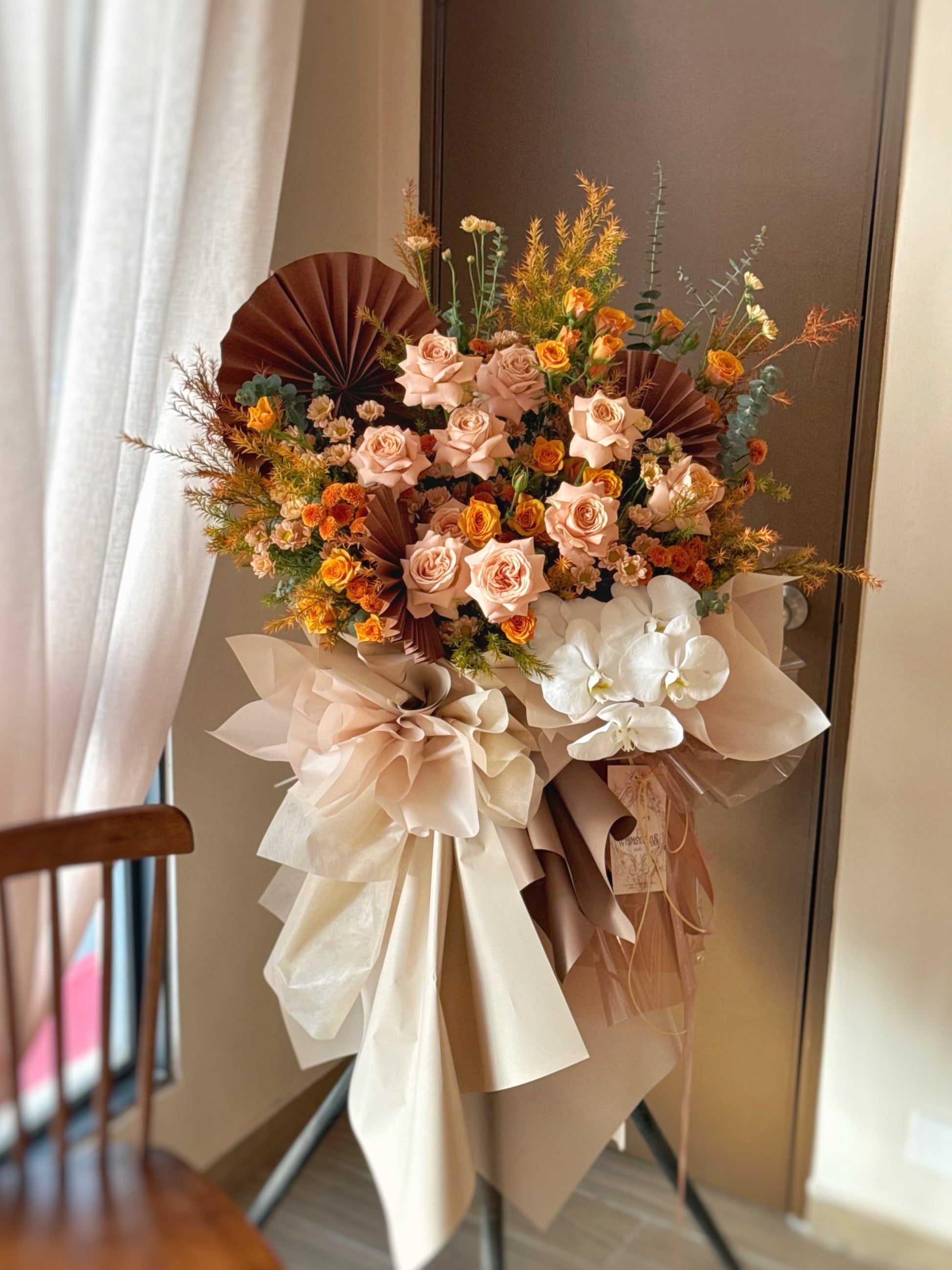 Front view of a grand opening flower stand featuring cappuccino roses in earthy amber, beige, and terracotta tones with lush greenery.

 正面展示开张花篮，焦糖玫瑰搭配琥珀、米色与赤陶色调，点缀丰盈绿叶，气质沉稳大气。