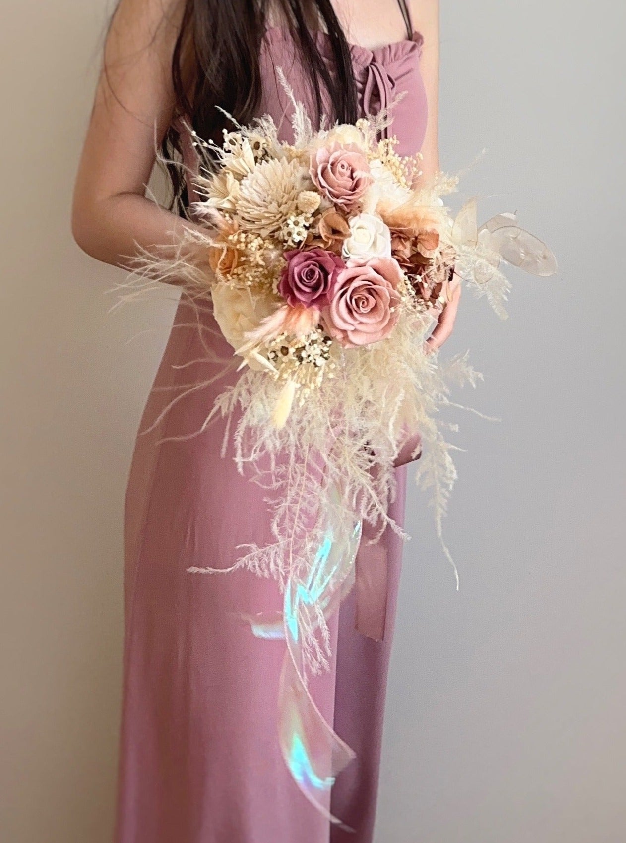 A bride holding the pastel cascading bouquet, adding an enchanting touch to her wedding look.
新娘手持柔和粉色瀑布型捧花，增添迷人梦幻感。