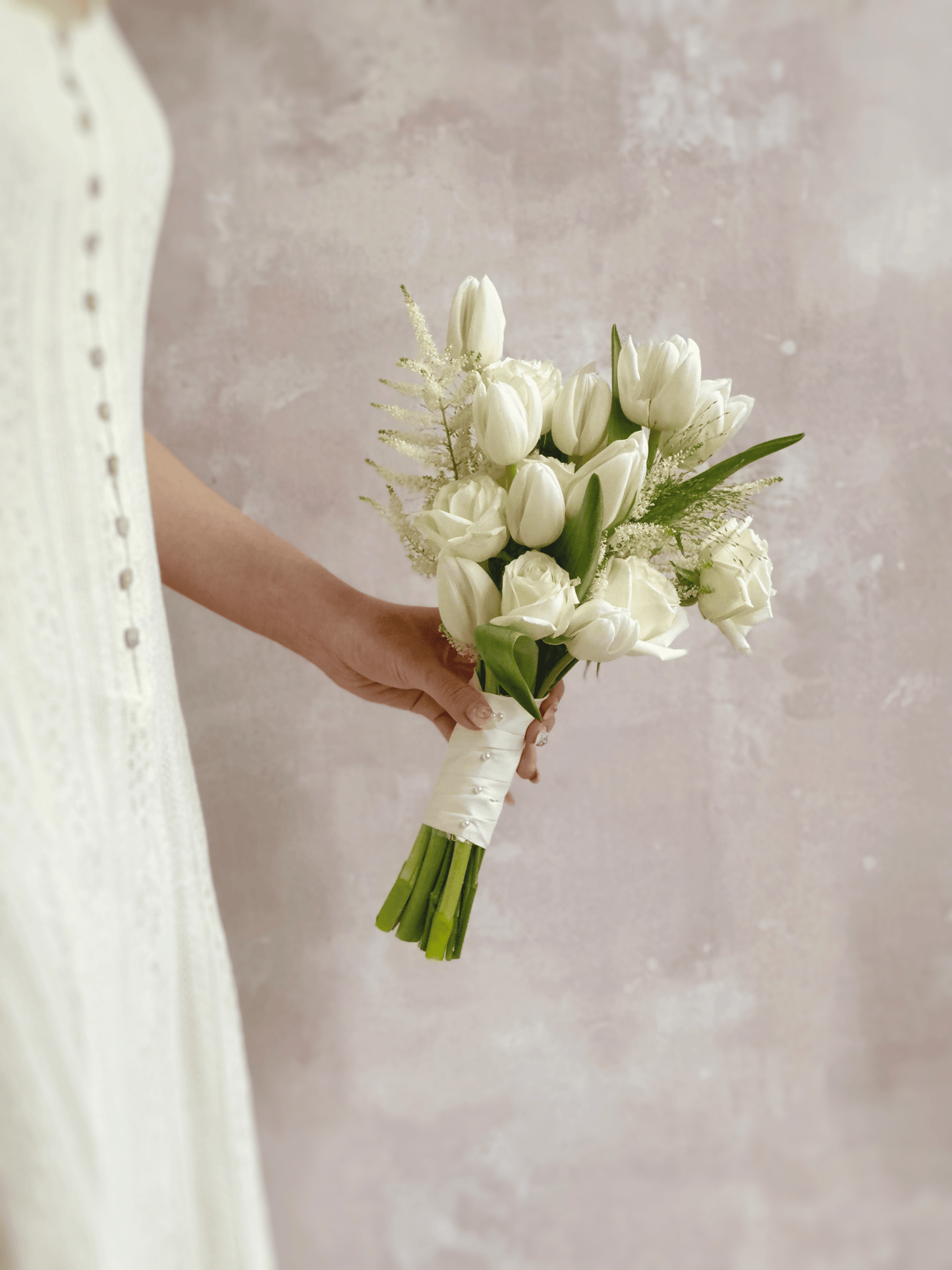 A side view of the bouquet, showcasing the flowing greenery and perfectly arranged white florals for a balanced, airy look.
从侧面欣赏捧花，绿叶自然垂落，白色花朵错落有致，呈现轻盈感。