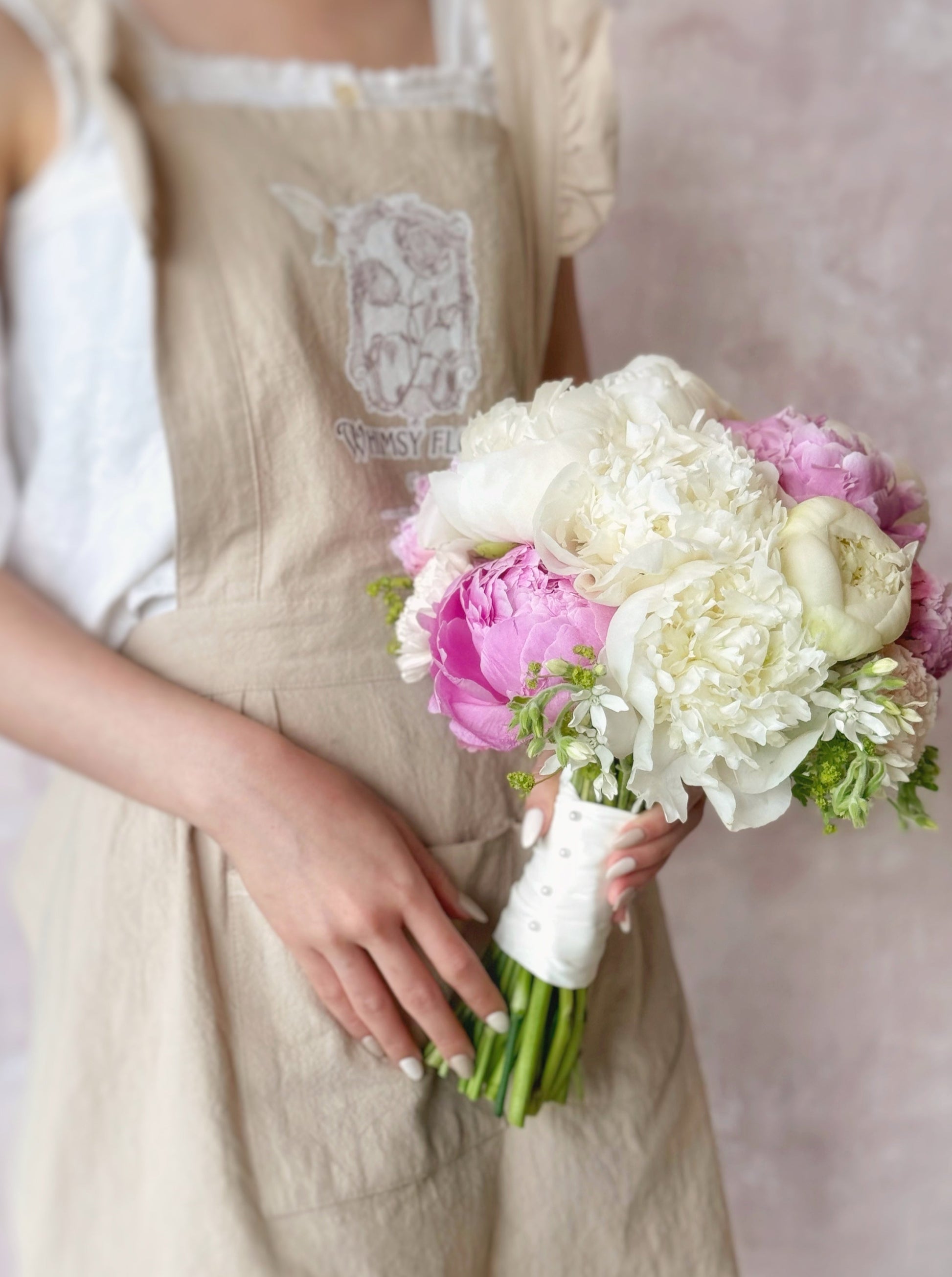 Photo of a model holding a bouquet of pink and white peonies, radiating elegance and romance with every delicate bloom
新娘手持丰盈的粉白牡丹捧花，尽显优雅与浪漫;令人惊艳的粉白牡丹新娘捧花，为婚礼增添浪漫与梦幻气息