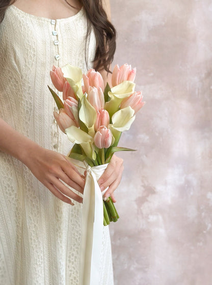 The calla lilies and tulips bouquet’s clean and refined look beautifully complements the bride’s natural and effortless wedding style.
白色郁金香马蹄莲捧花的简约精致风格，与新娘自然优雅的婚礼造型相得益彰。