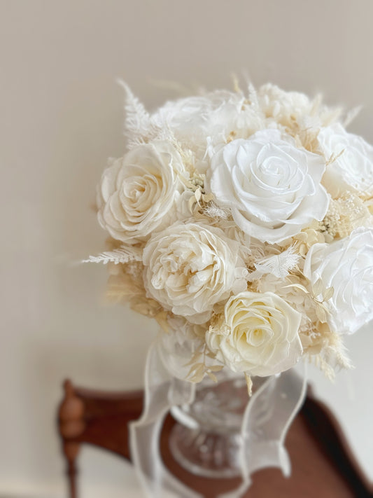 A delicate preserved round bouquet in soft white and creamy tones, exuding timeless elegance and dreamy charm.
一款精致的圆形永生花捧花，柔和的白色和奶油色调，散发出永恒优雅与梦幻气息。