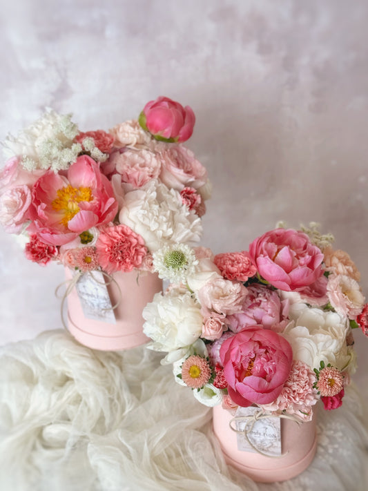 Close-up view of Sunkissed Peony bloom box, with the vibrant cherry pink coral sunset peony as the focal point, surrounded by a mix of seasonal blooms in a compact arrangement