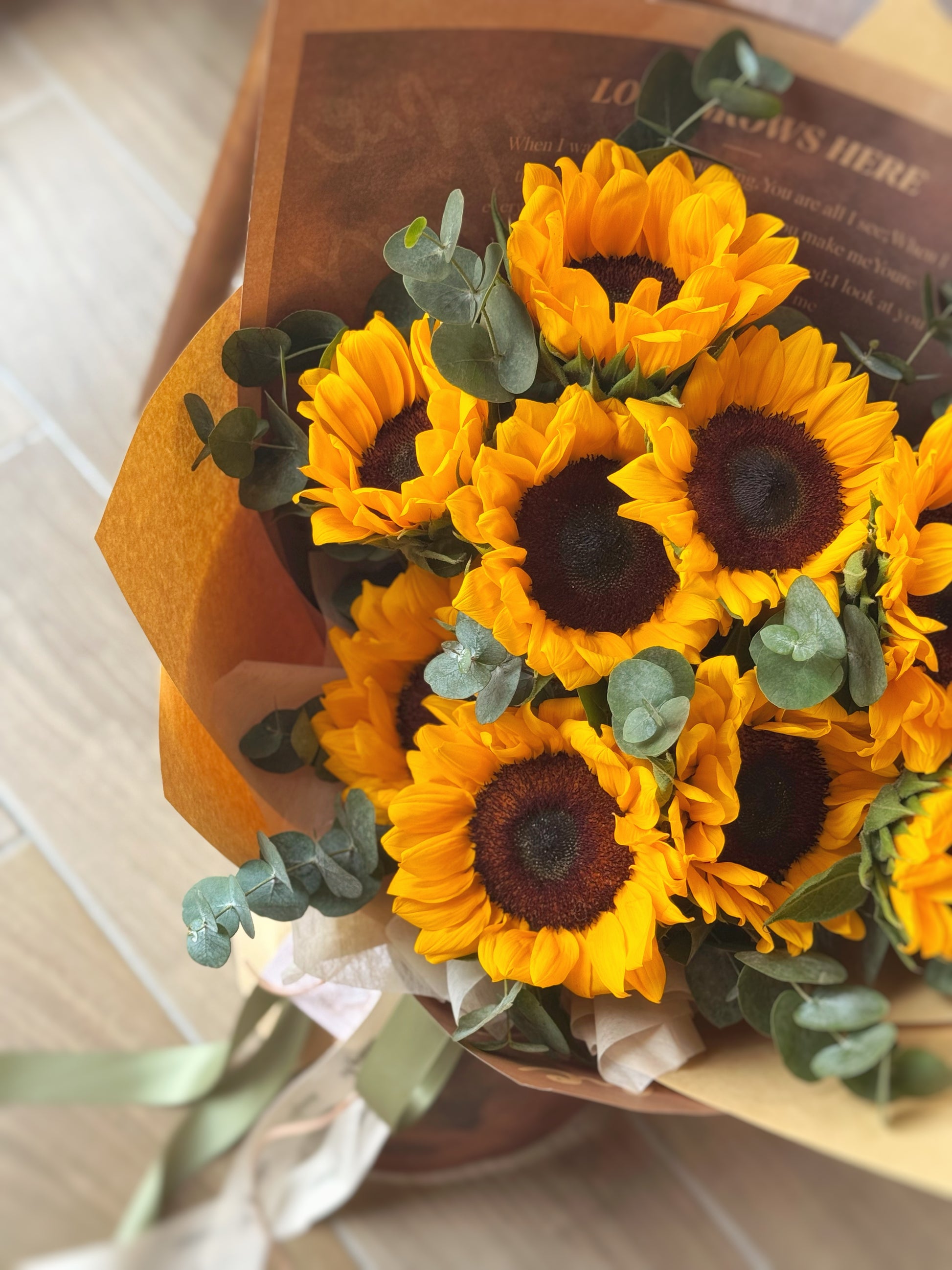 Close-up of bold sunflower heads and fresh eucalyptus leaves, capturing natural textures and golden tones.
向日葵花头与尤加利叶特写，突显自然纹理与金黄色调的清新活力。