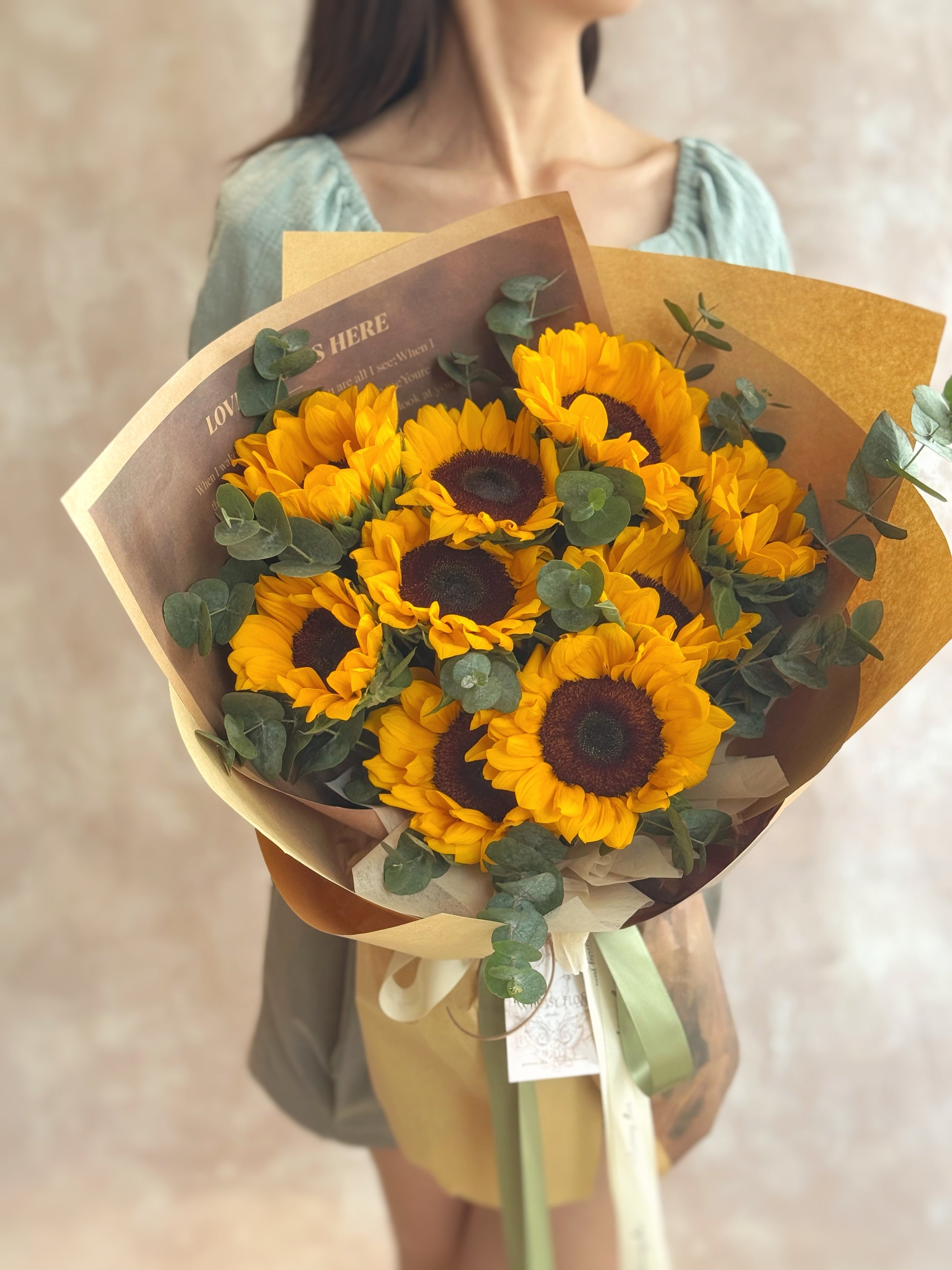 Bouquet held in hand by a model, capturing the sunny and joyful charm of the sunflowers in a casual, rustic look.

模特手持花束，展现向日葵阳光快乐的氛围与随性田园风格。

