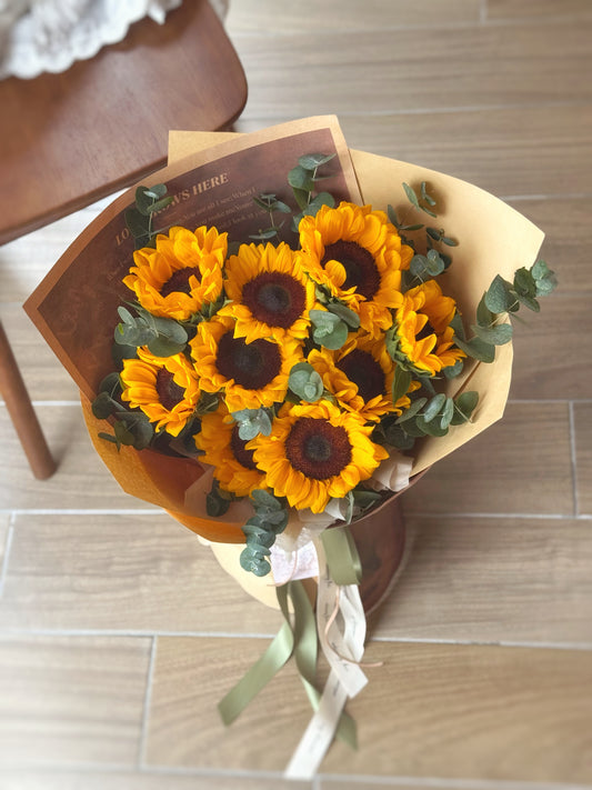 Top-down view of the bouquet showcasing a tight, bright arrangement of sunflowers with eucalyptus accents.
俯视图展现向日葵紧密排列的结构，点缀尤加利叶，整体明亮协调。