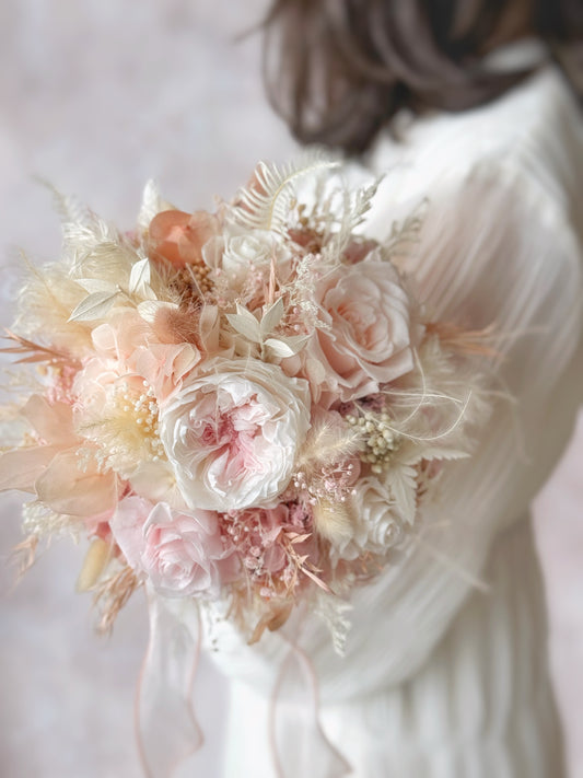 Tea rose preserved flowers round shaped bridal bouquet in front of model. A detailed close-up of the preserved floral textures, highlighting the soft petals and intricate details of each bloom.
特写镜头捕捉永生花的细腻质感，展现每一朵花瓣的柔软与精致细节。