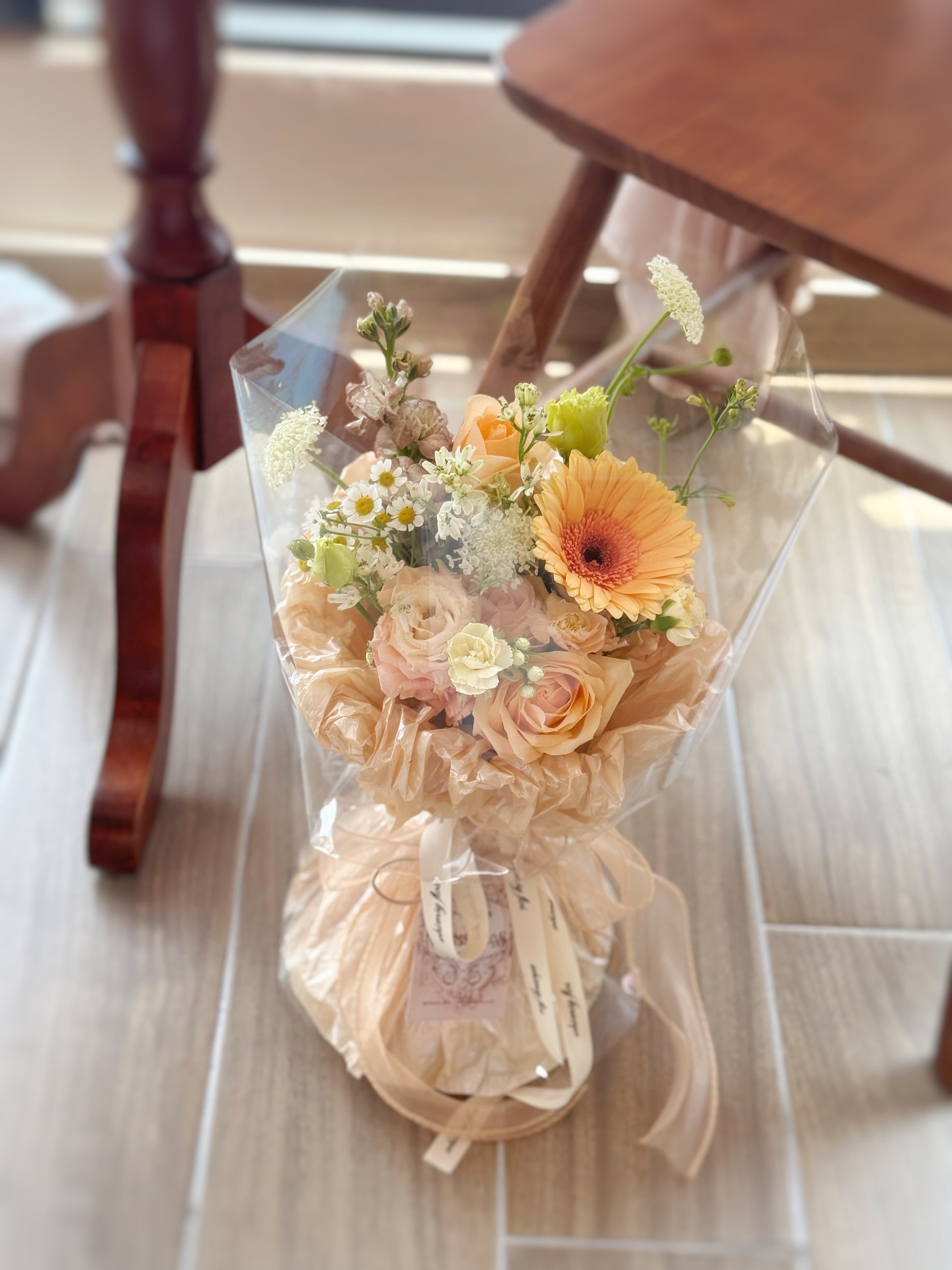  Top-down view showing a balanced mix of muted floral tones — peach, cream, and khaki — with airy green foliage.
俯视图展示柔和色调花材如蜜桃、奶油与卡其，搭配轻盈绿叶，自然协