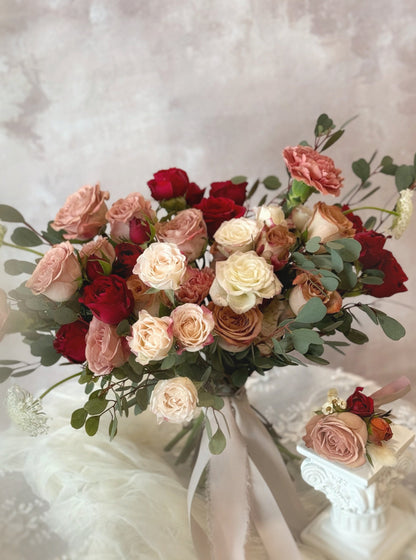 A vintage-style bridal bouquet paired with a matching maroon rose boutonniere for the groom
复古风新娘捧花，搭配酒红玫瑰胸花，打造完美婚礼配套