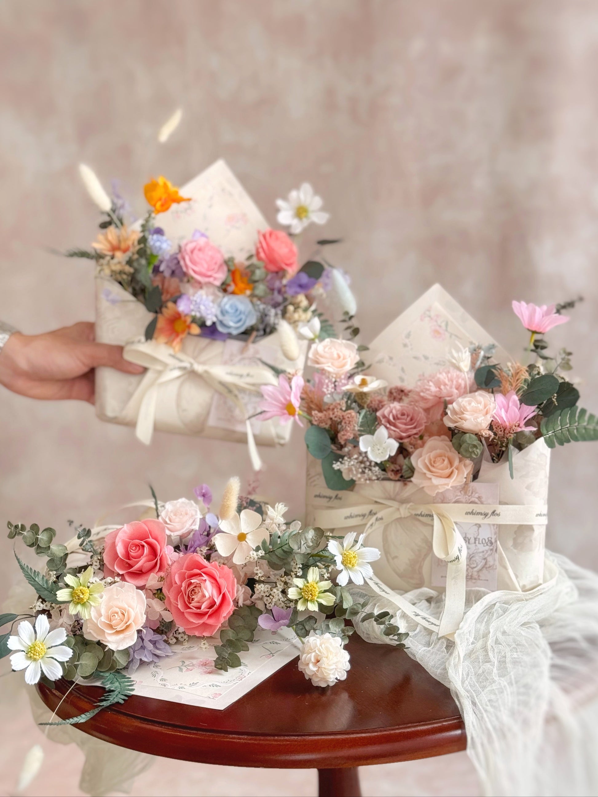 Whimsical Envelope floral gift displayed on a table—an elegant envelope-style design blooming with vibrant preserved and dried flowers, perfect for Mother’s Day or 520 gifting.
Whimsical Envelope花礼摆放在桌面上，信封造型中盛放着色彩鲜明的永生花与干燥花，是母亲节或520的理想小礼物。
