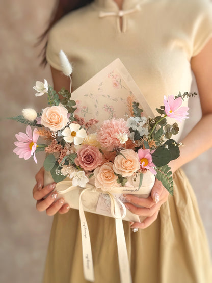 Hand holding a Whimsical Envelope floral gift with a pop of colorful blooms, showcasing its unique mini envelope shape and cheerful tones.
手持Whimsical Envelope花束，色彩丰富的花材从优雅信封中溢出，散发浪漫与童趣。