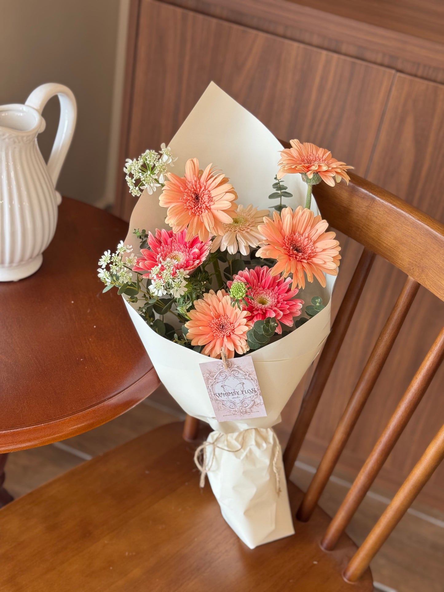 Bouquet laid or placed upright on a wooden chair, styled as if freshly brought home — bright, joyful, and vase-ready.

花束平放或直立于木椅子表面，营造刚买回家的花艺氛围，色彩鲜亮，充满生活感。

