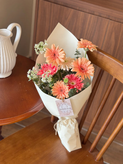 Bouquet laid or placed upright on a wooden chair, styled as if freshly brought home — bright, joyful, and vase-ready.

花束平放或直立于木椅子表面，营造刚买回家的花艺氛围，色彩鲜亮，充满生活感。

