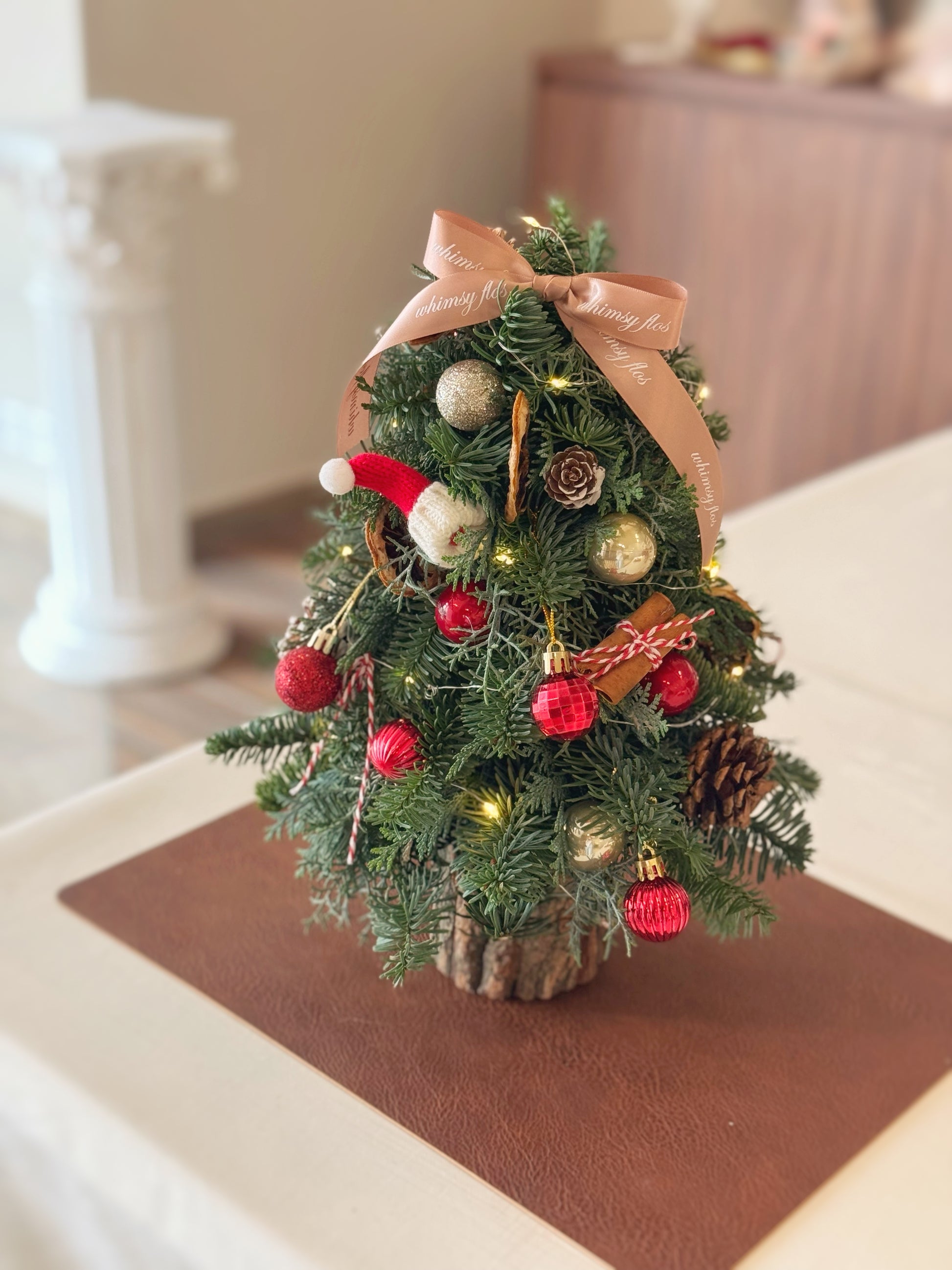 Red-themed 35 cm mini Christmas tree with Santa hat, decorated for a cute holiday look.
红色主题 35 厘米迷你圣诞树，配圣诞老人帽，装饰可爱节日风。