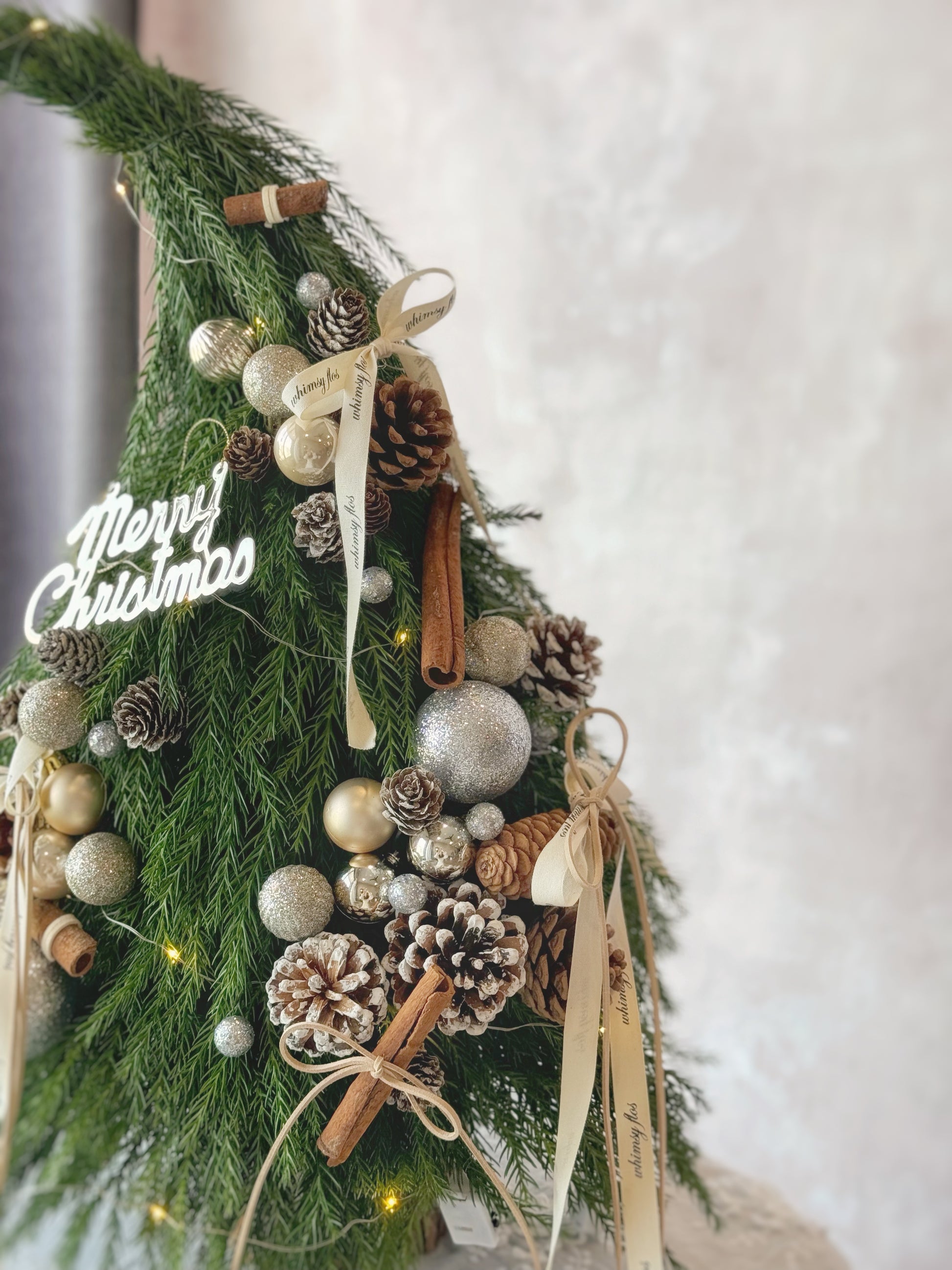 Close-up of the Grinch Tree showing fresh pine texture, pinecones, and neutral woodland decorations.
Grinch Tree 细节特写，可见新鲜松枝、松果与自然森系装饰。