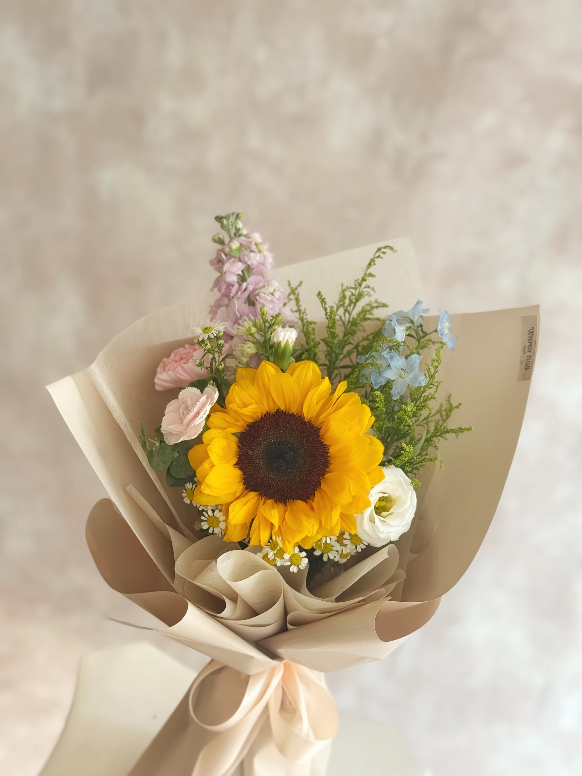  Close-up of the sunflower center, with soft-petaled pastel flowers and daisy accents framing it in gentle textures.

 向日葵花心特写，柔和花瓣的粉色系小花与小雏菊相互衬托，细节温柔可爱。